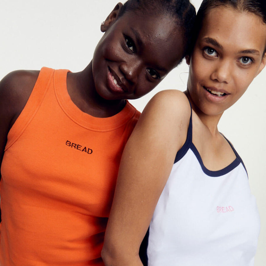 Two women stand smiling one wearing a Bread tank.